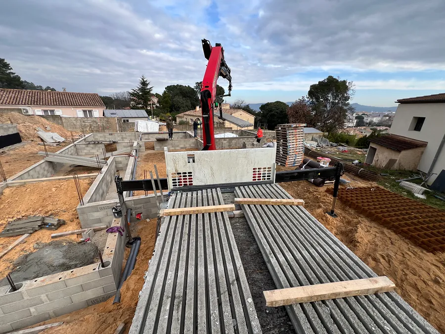 Camion-grue déchargeant des poutrelles en béton sur le chantier