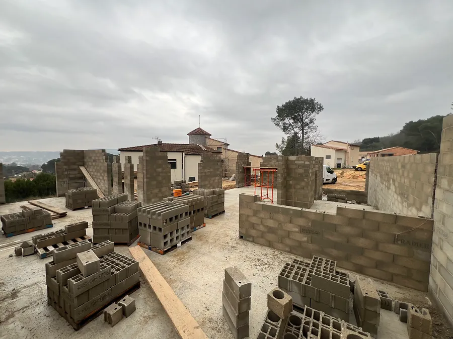 Murs de la maison en cours d’élévation en blocs béton, palettes de blocs sur la dalle