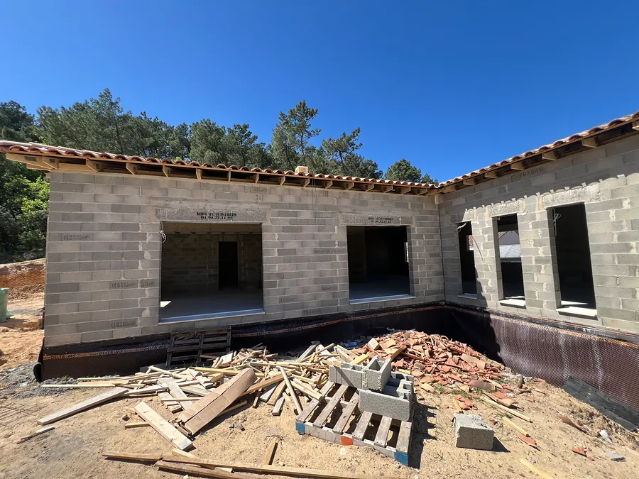 Maison en L en blocs béton avec toiture en tuiles, avant les enduits
