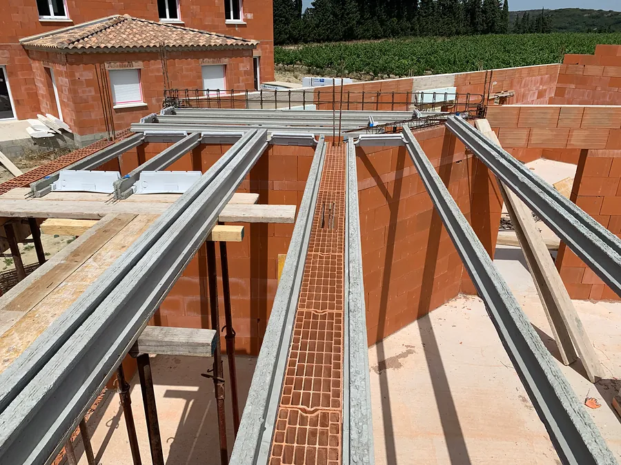 Poutrelles posées pour le plancher de l’étage entre les murs en brique